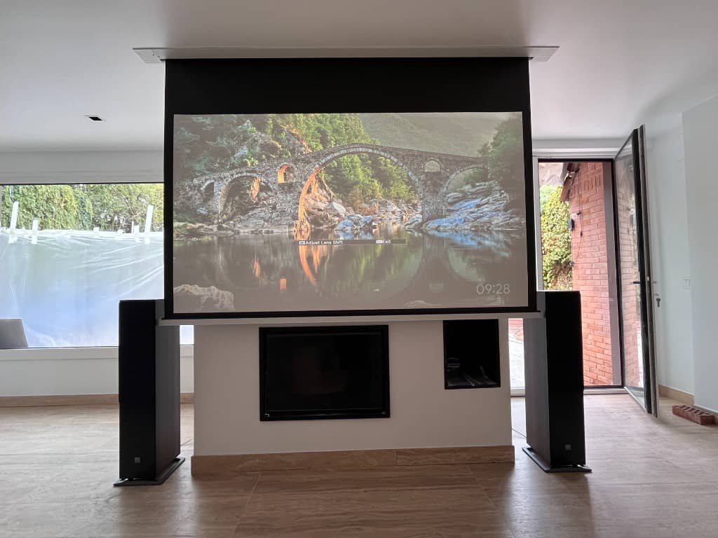 Salón de chalet con pantalla motorizada, chimenea y vistas al jardín