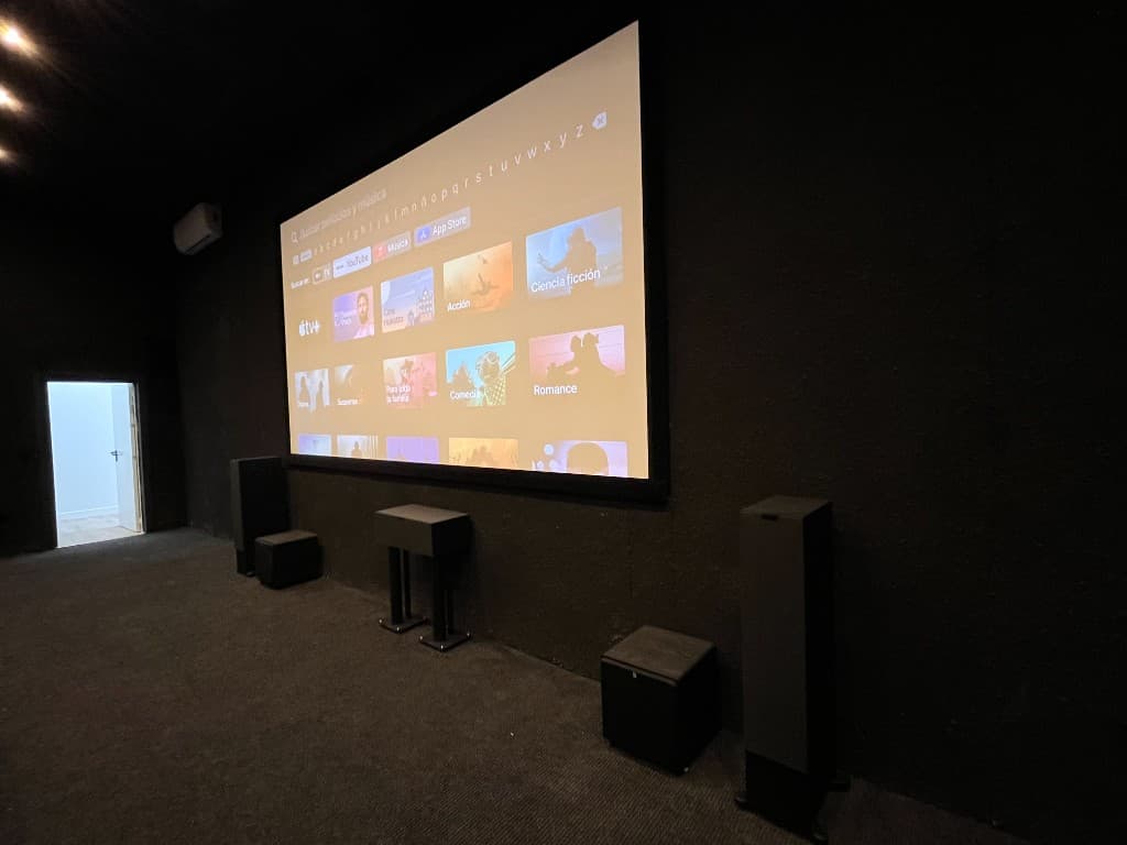 Sala de cine dedicada en chalet con pantalla, torre de altavoces y acústica